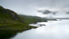 Misty view of a serene fjord and fish farm in Troms og Finnmark, Norway.