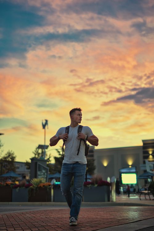 Free Young man in denim and white shirt exploring cityscape at vibrant sunset. Stock Photo
