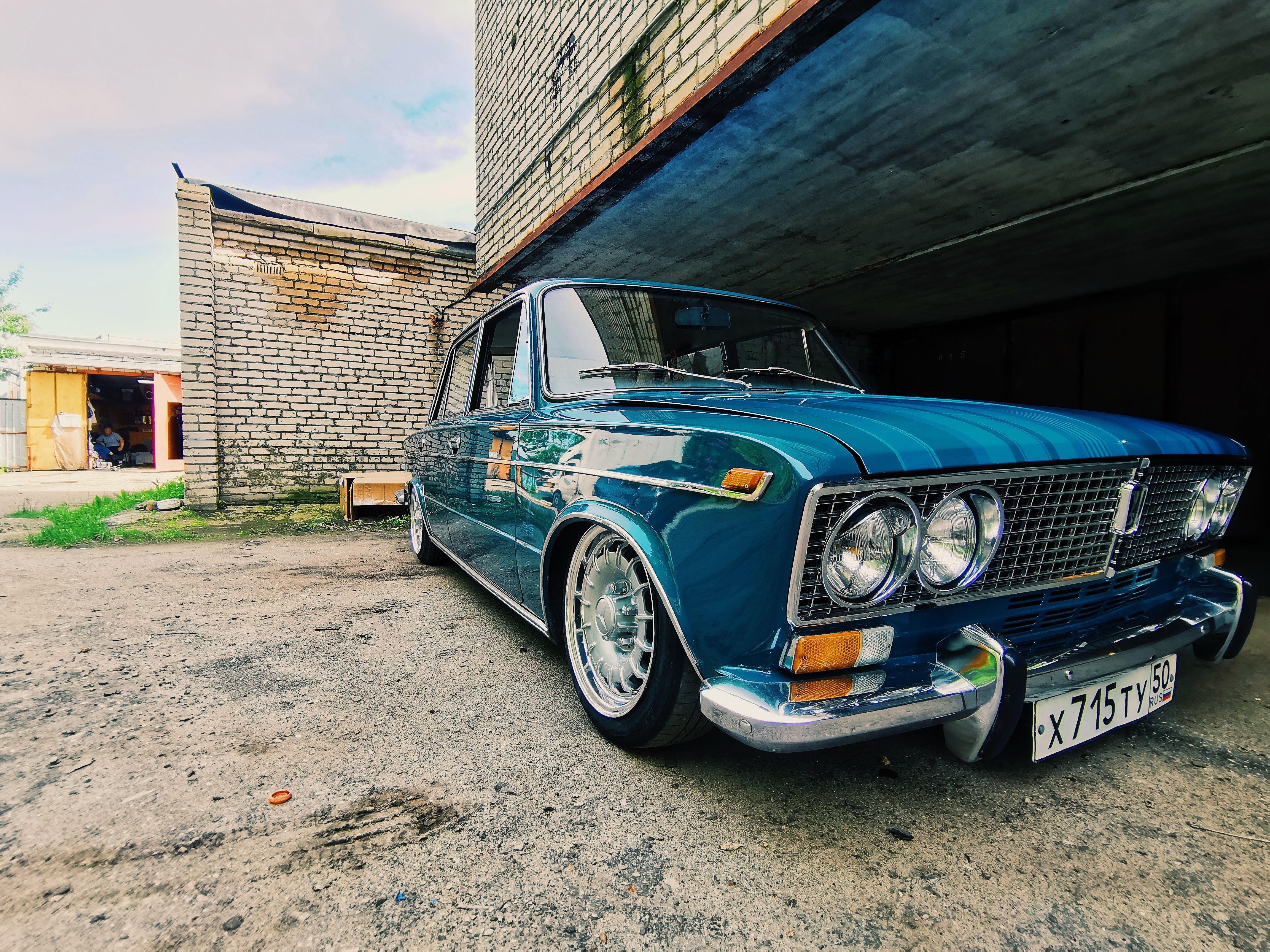 A classic VAZ-2103 in blue parked under a concrete structure, showcasing vintage charm.