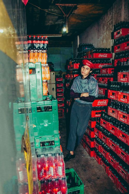 Free Warehouse staff posing among stacked soda crates in a dim storage area. Stock Photo