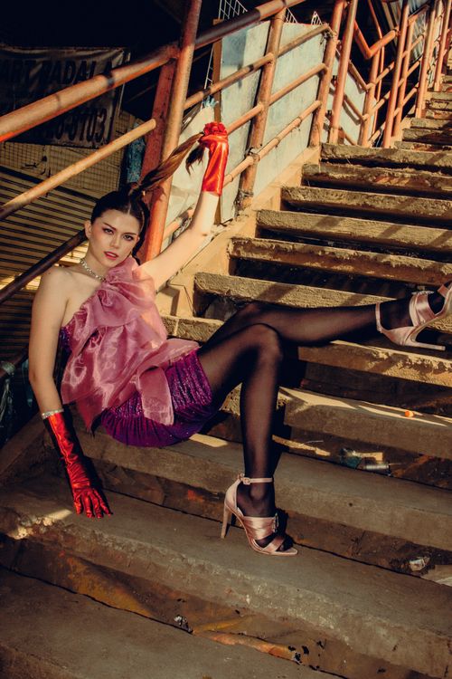 Free Stylish model poses on urban stairs in vibrant outfit and red gloves. Stock Photo