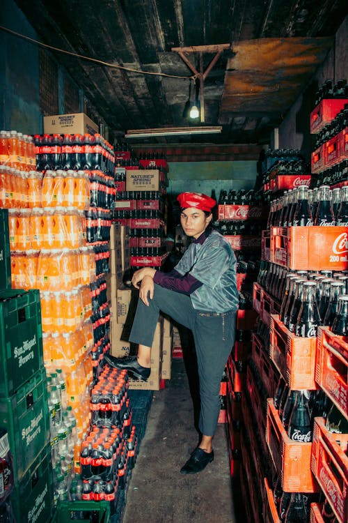 Man Posing in Warehouse Full of Colorful Crates of Soda