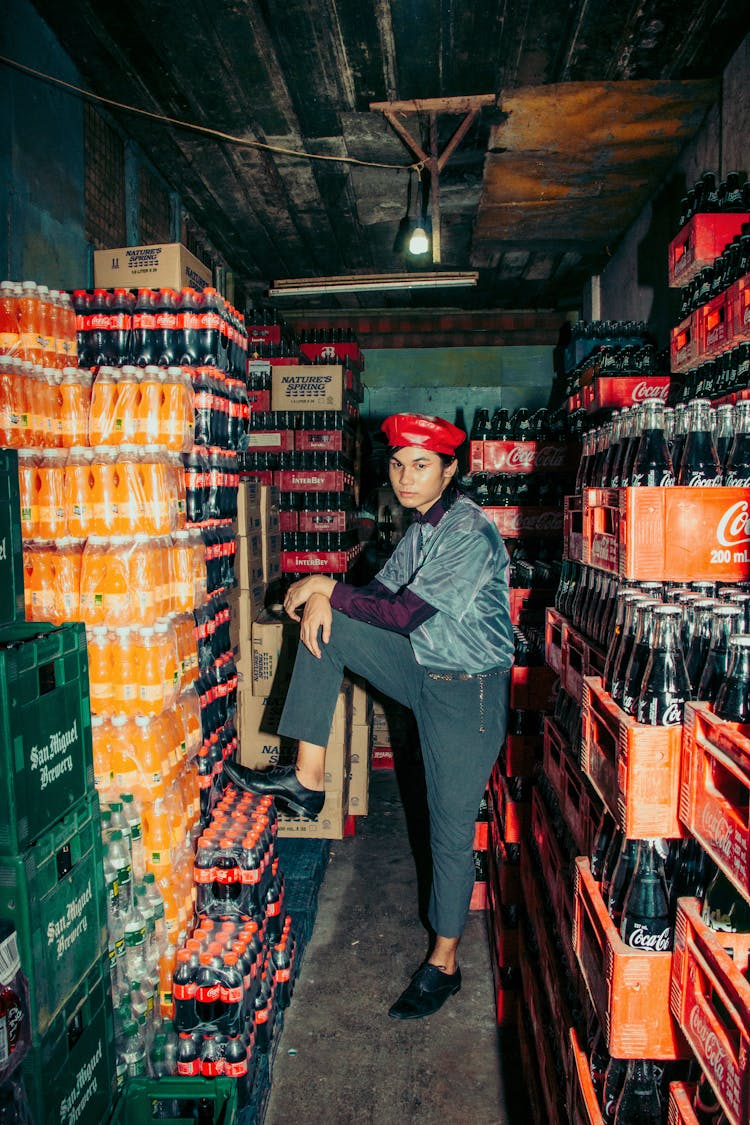 Man Posing In Warehouse Full Of Colorful Crates Of Soda