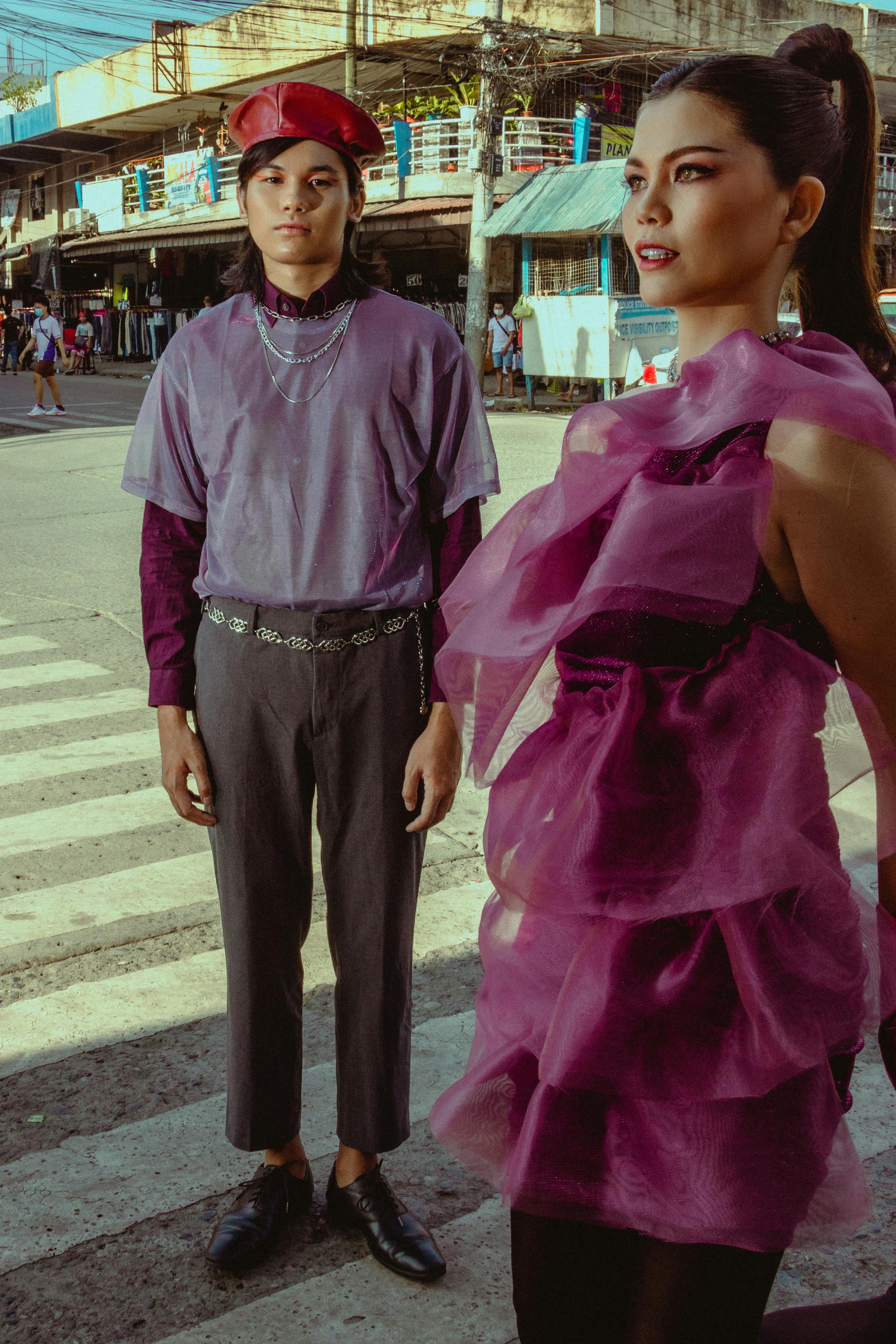 Stylish couple in vibrant outfits standing on a city pedestrian crossing.