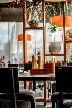 A modern restaurant interior featuring elegant decor, plant arrangements, and warm lighting.
