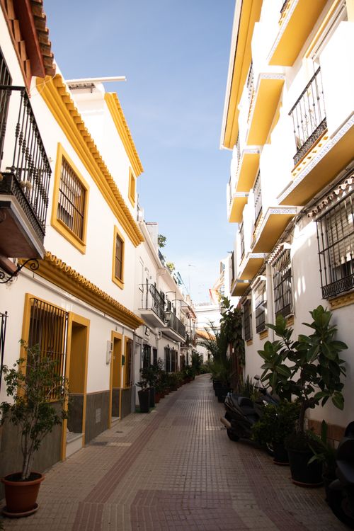 Free A quaint narrow alley in a Spanish town, showcasing traditional architecture and vibrant colors. Stock Photo