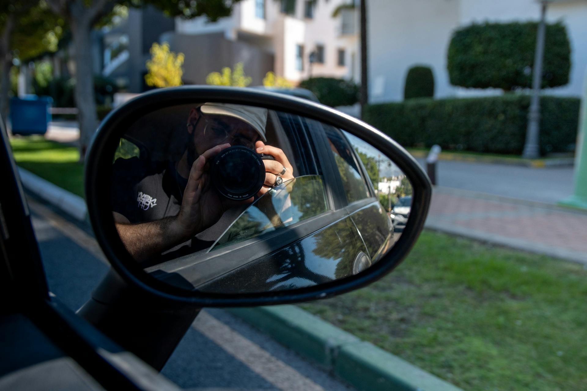 Reflection of a Man Holding a Camera over a Car Side Mirror