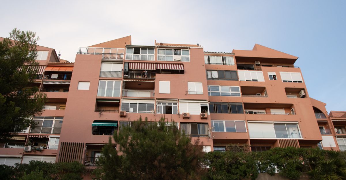 A modern brown apartment building with balconies against a clear blue sky.
