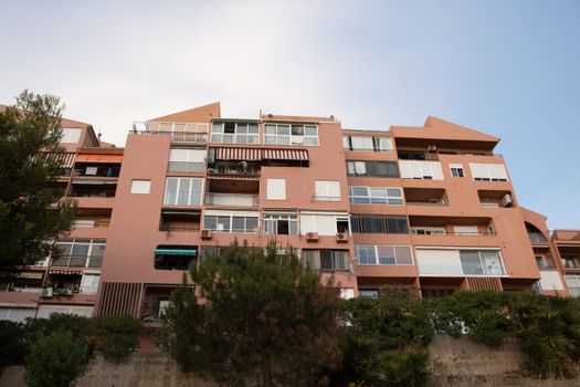 A modern brown apartment building with balconies against a clear blue sky.
