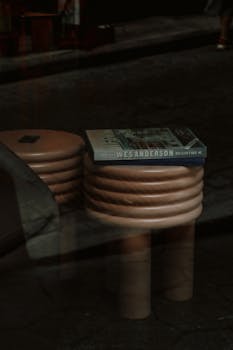 A Wes Anderson book resting on a unique wooden stool inside a modern interior setting.