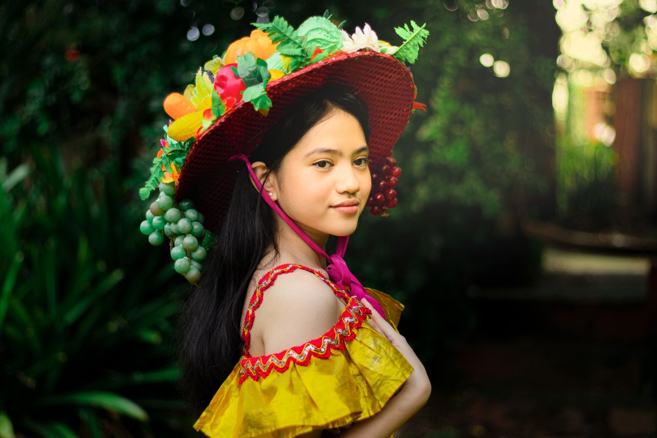 vibrant portrait of a young woman wearing a colorful fruit themed hat