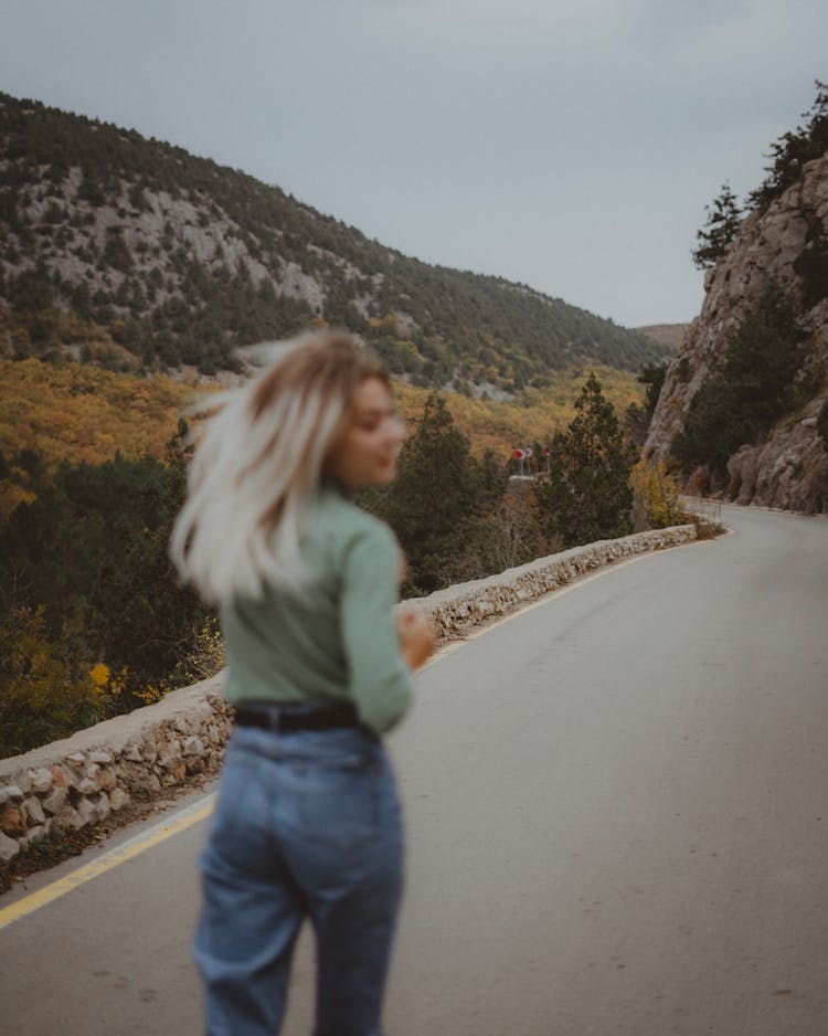 Blonde Woman Running On The Road Near The Rock Mountain