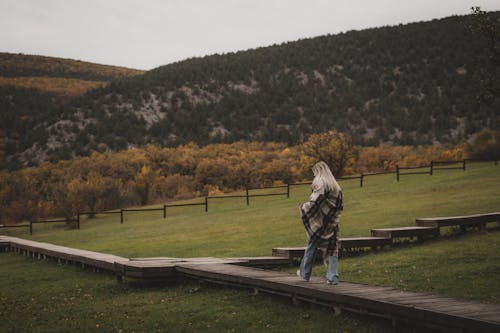 A Woman Walking on Wooden Walkway in the Countryside