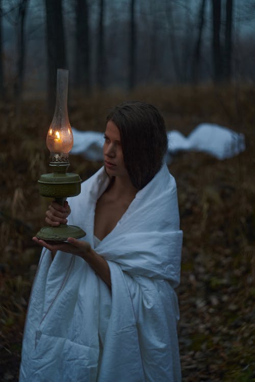 Free Woman Wrapped with a Blanket Holding a Lamp Stock Photo