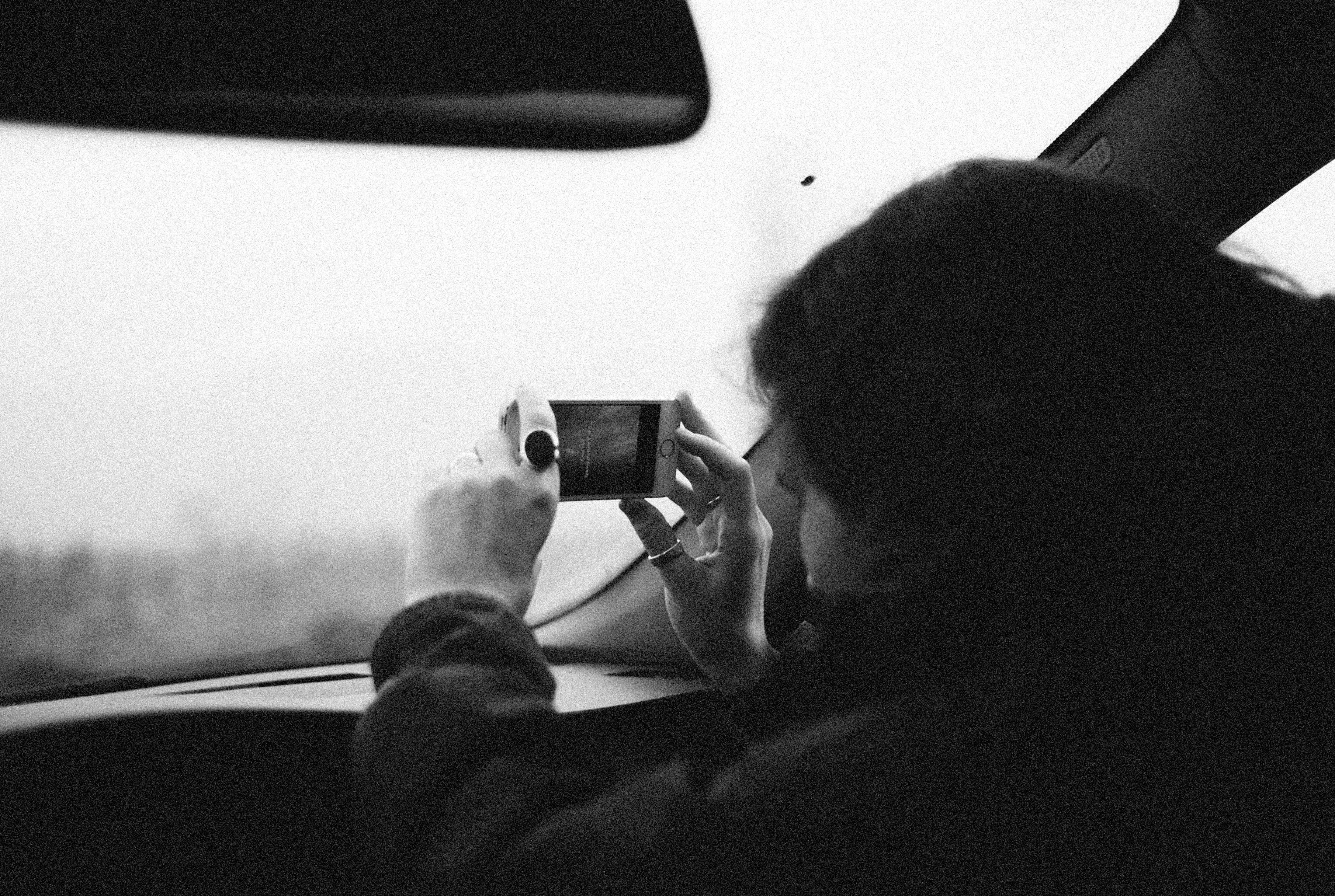 grayscale photo of a person taking picture using a smartphone