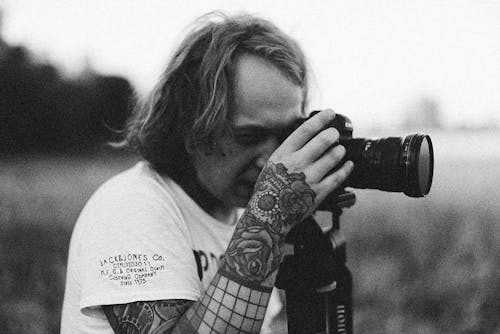 Free Grayscale Photo of a Tattooed Man Taking Photos Using a Digital Camera Stock Photo