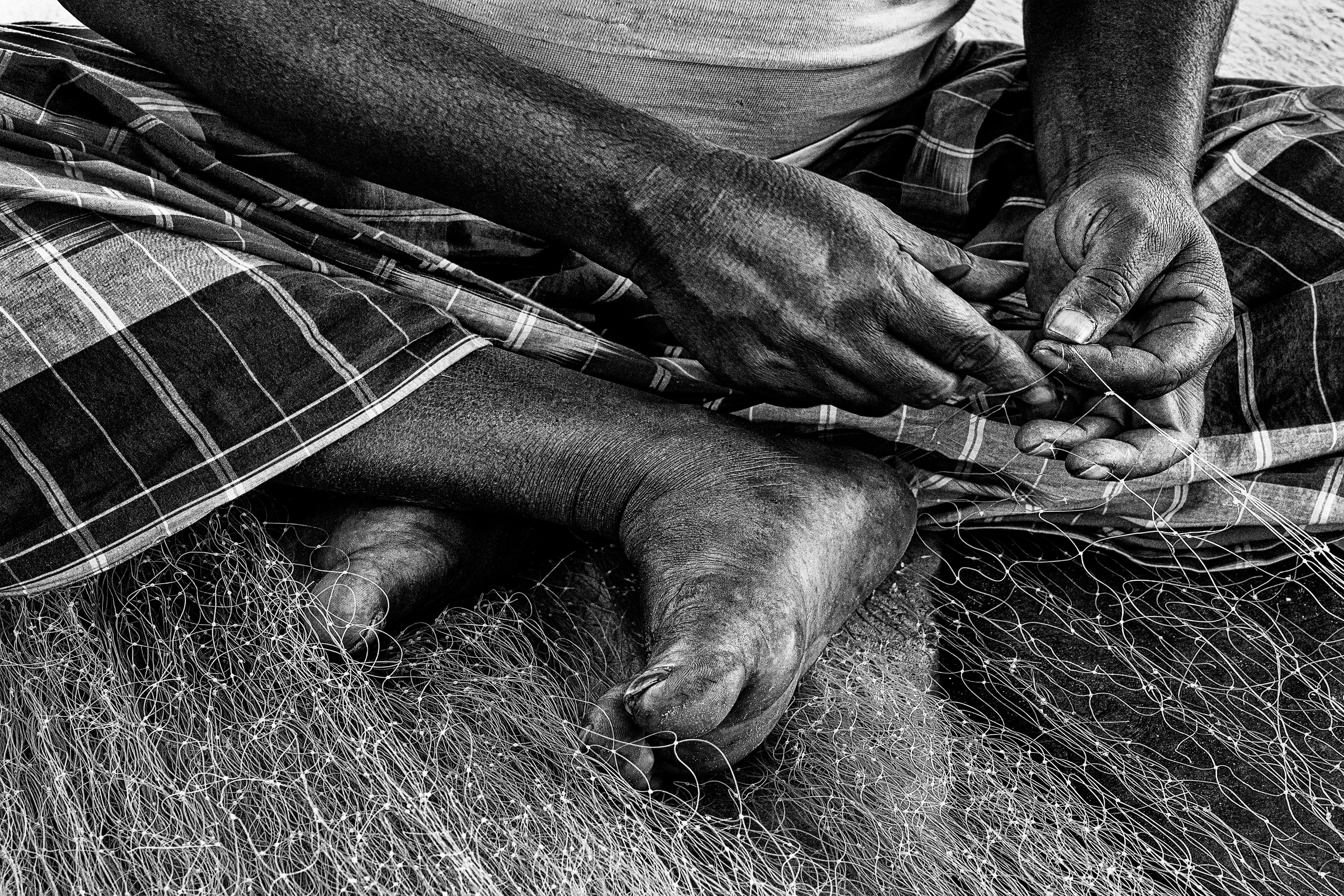 Close-up of hands skillfully weaving a fishing net, highlighting traditional craftsmanship.