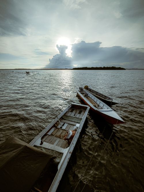 Free Peaceful scene of wooden boats moored on a calm lake during sunset, capturing reflections and vibrant skies. Stock Photo