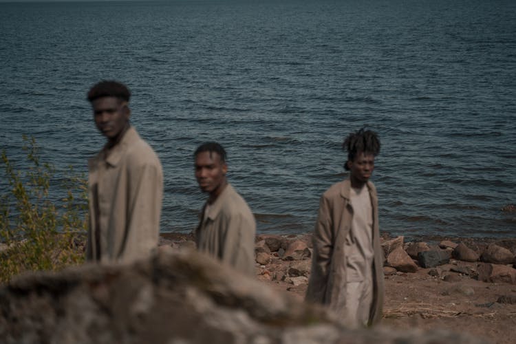 Beautiful Calm Sea Behind Three Men Standing On Beach Shore