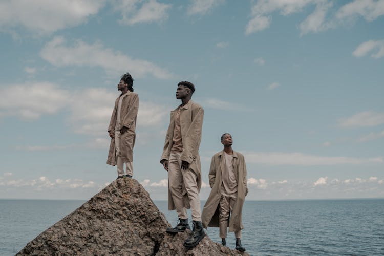 Small Group Of Pensive Men Standing On Cliff Rock