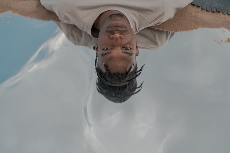 High Angle Portrait Of Man Laying In Water Reflecting Sky