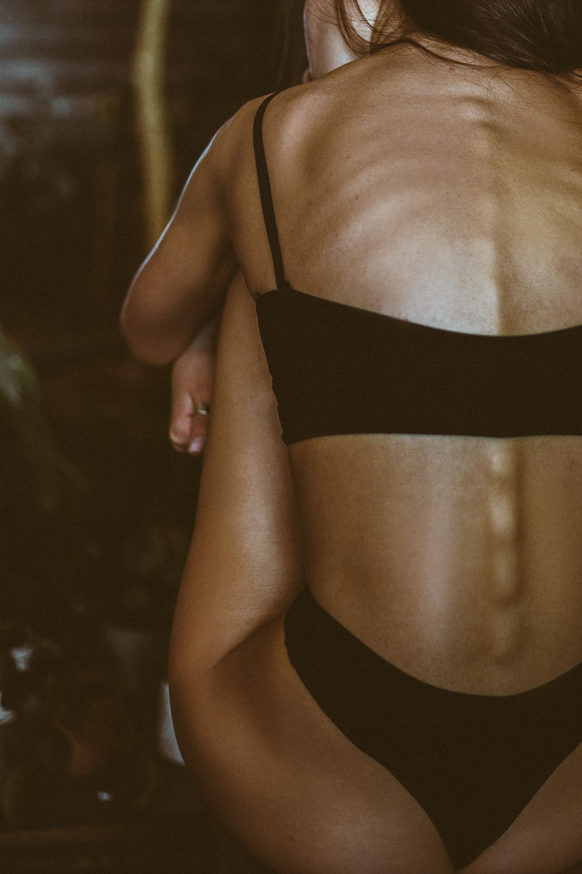 Artistic close-up of a woman in a black bikini, captured from behind, highlighting the natural form.