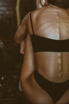 Artistic close-up of a woman in a black bikini, captured from behind, highlighting the natural form.