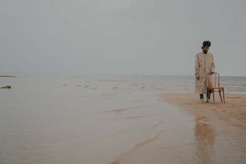 Free A Man in a Coat Standing on the Shore Stock Photo