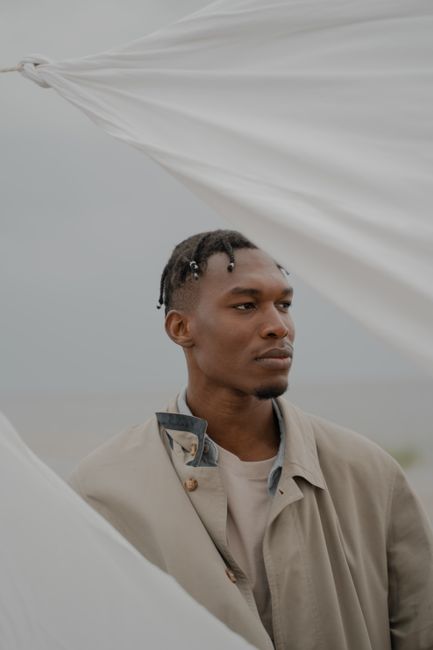 Portrait of a man with braided hair outdoors, highlighting style and contemplation.