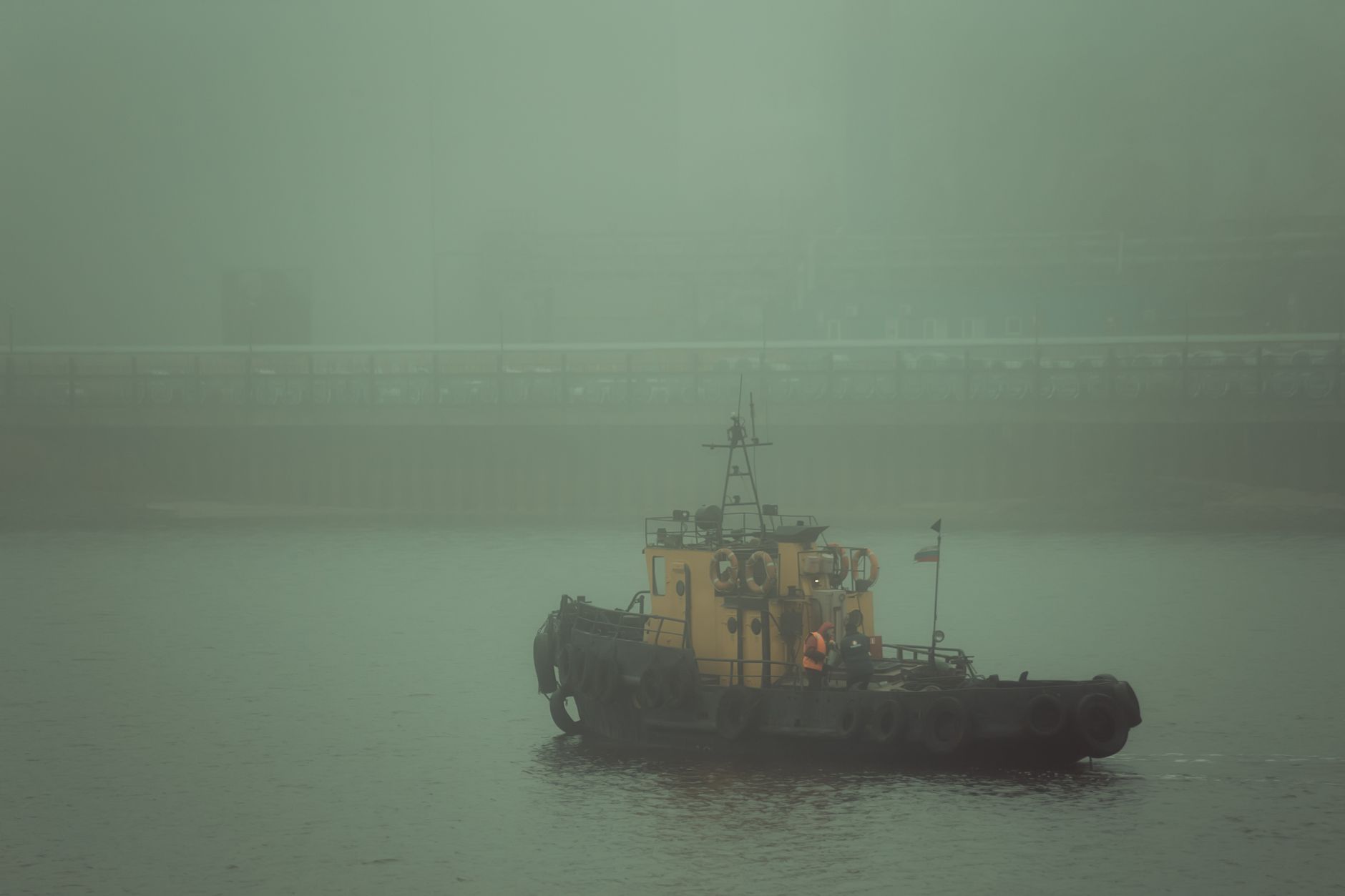 A tugboat navigates through dense fog in Cherepovets harbor, creating a mysterious atmosphere.