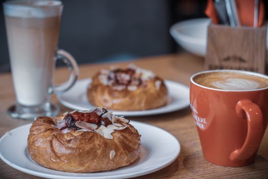 Warm and inviting coffee break featuring cappuccino and pastries on a wooden table.