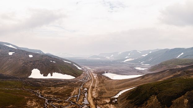 A breathtaking aerial view of a snow-dusted valley in Kamchatka, Russia, with rugged mountains.
