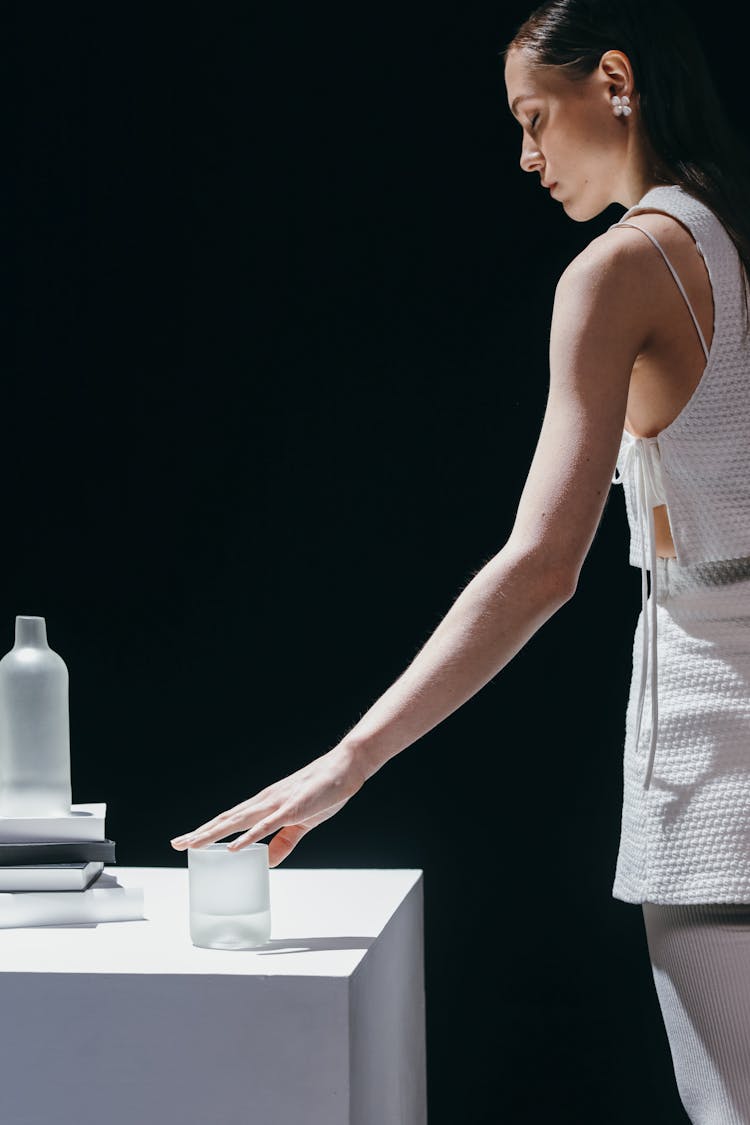 A Woman In White Outfit Groping The Glass On The Table