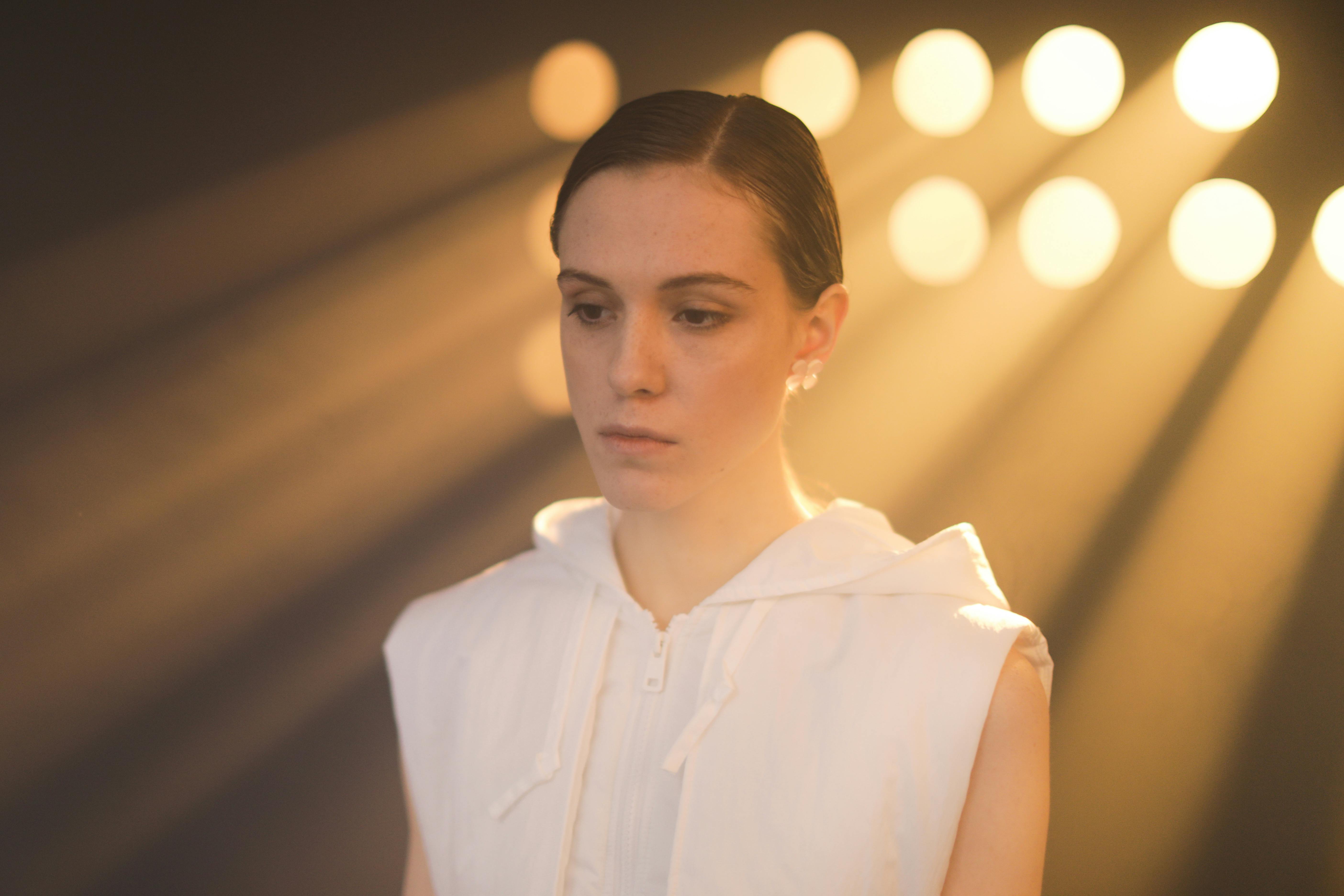 一位穿着白背心的女人在圆形灯光的戏剧性背光下的肖像