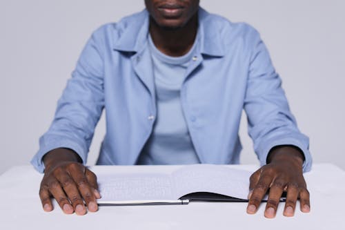 A Man in  Blue Long Sleeves Reading a Braille