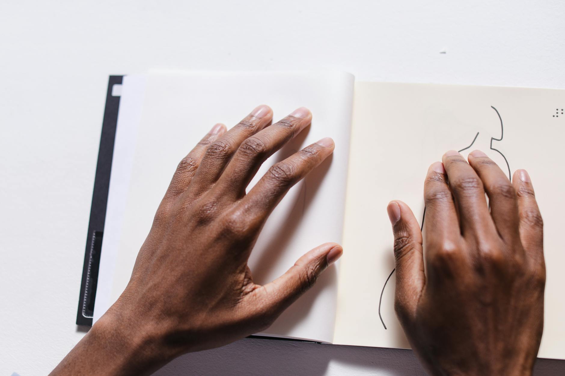 A Person's Hands on White Book