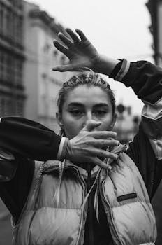 Black and white portrait of a woman posing expressively in a city street.