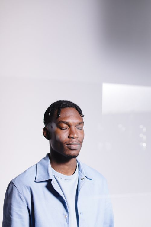 Free Fashion portrait of a man wearing a blue shirt, eyes closed against a white background. Stock Photo