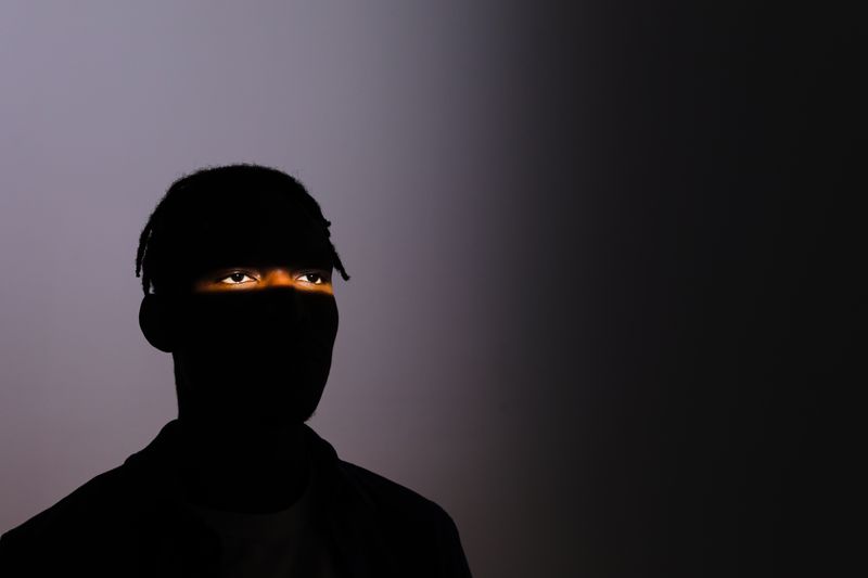 A silhouette of a man with only his eyes illuminated, conveying mystery and dramatic lighting.
