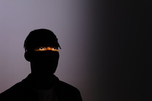 Free A silhouette of a man with only his eyes illuminated, conveying mystery and dramatic lighting. Stock Photo