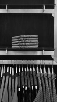 Elegant black and white display of folded shirts and hanging jackets in a store.