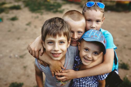 Free A cheerful group of young boys hugging and smiling outdoors, capturing playful happiness. Stock Photo
