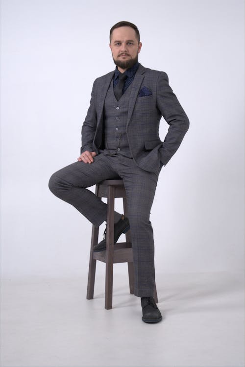 Man in Gray Suit Jacket Sitting on Brown Wooden Stool