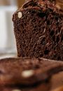 A Close Up on Dark Bread on Cutting Board With Glass of Milk in Background 