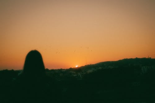 A Silhouette of a Female With a Sunset in a Background
