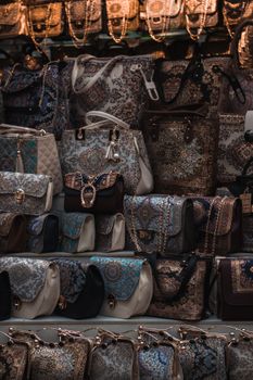 A close-up vertical shot showcasing various intricately designed handbags on display at a market stall.