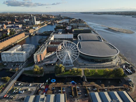 A stunning aerial view of Liverpool's waterfront featuring a prominent ferris wheel and modern cityscape.
