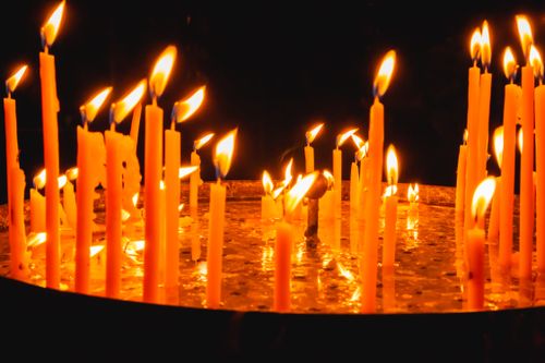 Free A close-up view of multiple candles burning in a dimly lit environment, showcasing their warm, flickering flames. Stock Photo