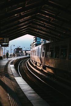 A train departs from a dimly lit urban station during twilight, capturing the city's bustling transport hub.