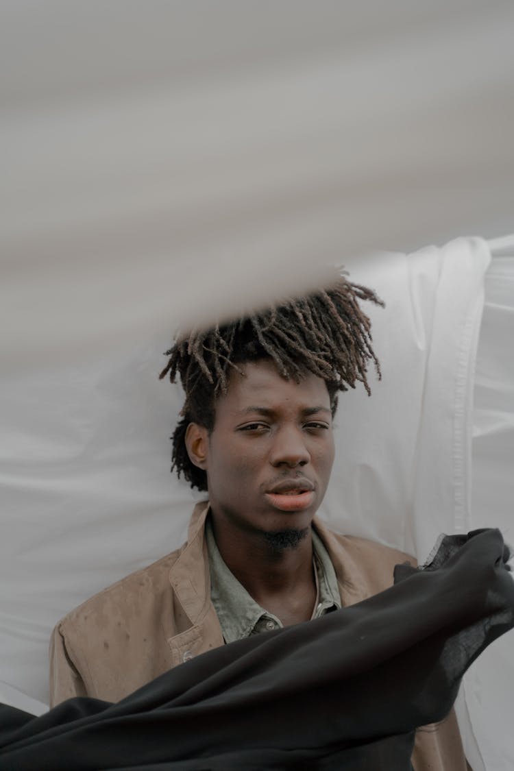 A Man With Dreadlocks Surrounded By Fabrics